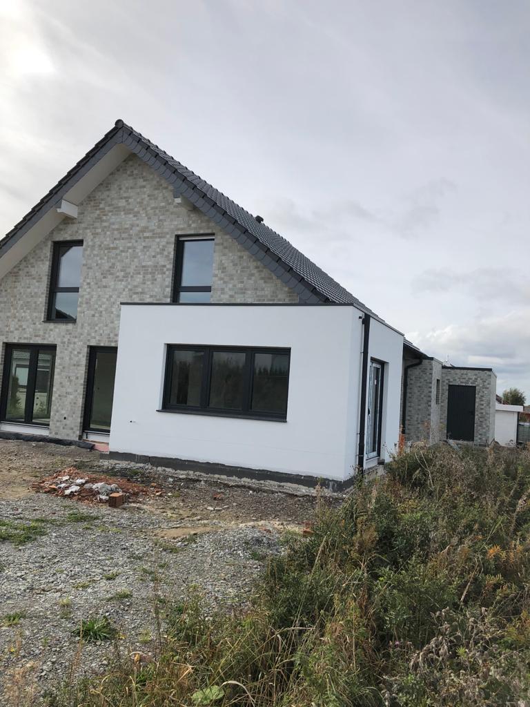 Wohnhausanbau mit fertig ausgeführtem Fassadenputz und dunklem Sockel