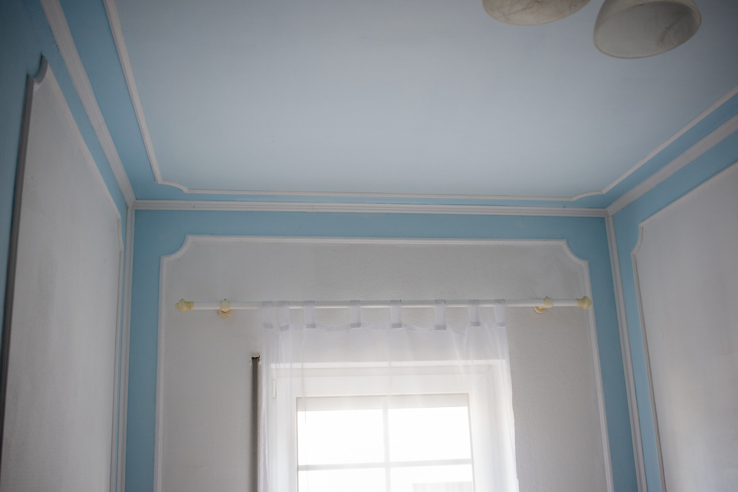 Deckenstuck mit umlaufender Stuckleiste in blau-weiß gestalteter Raumdecke