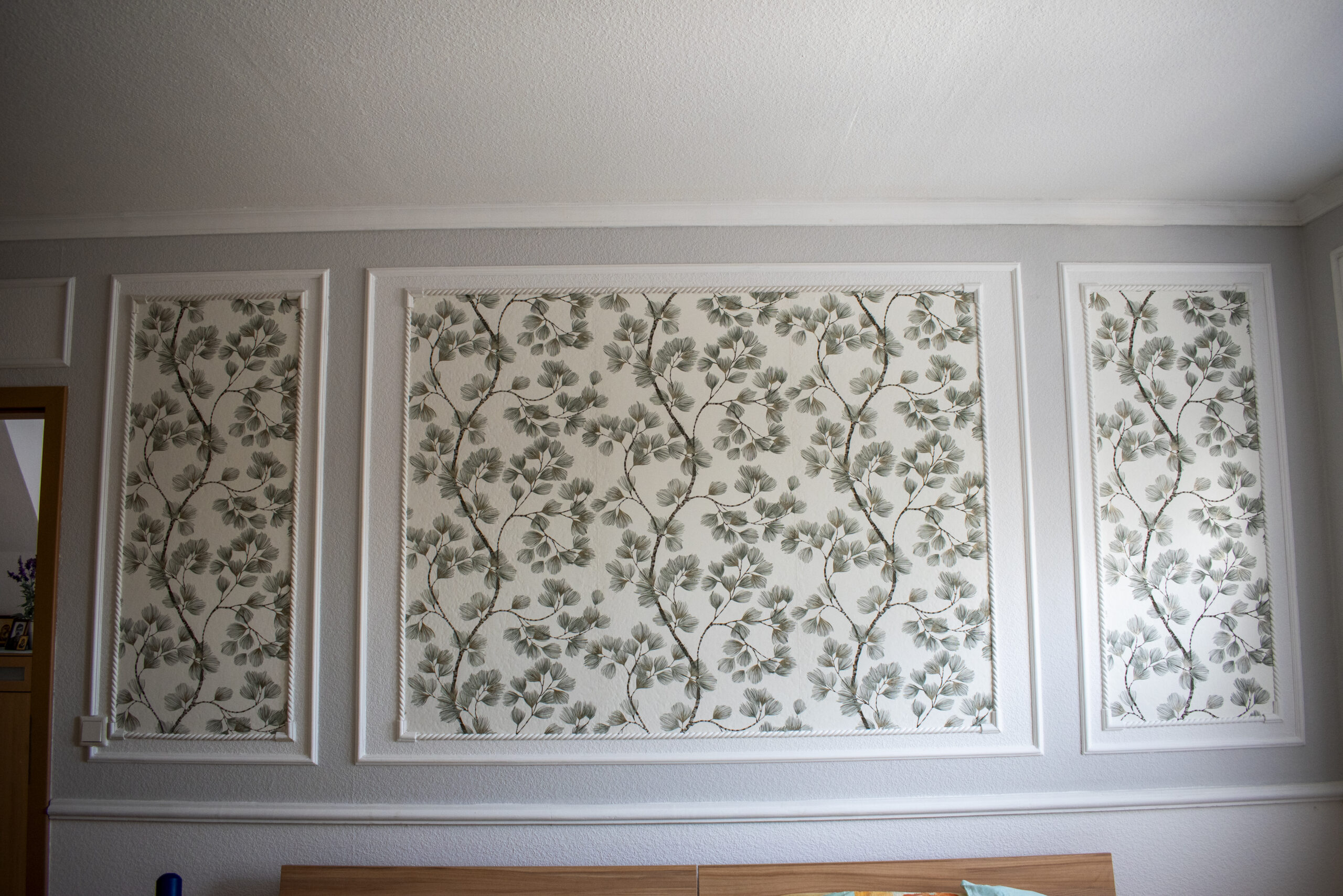 Wandgestaltung mit Stuckrahmen und dekorativer Tapete im klassischen Stil